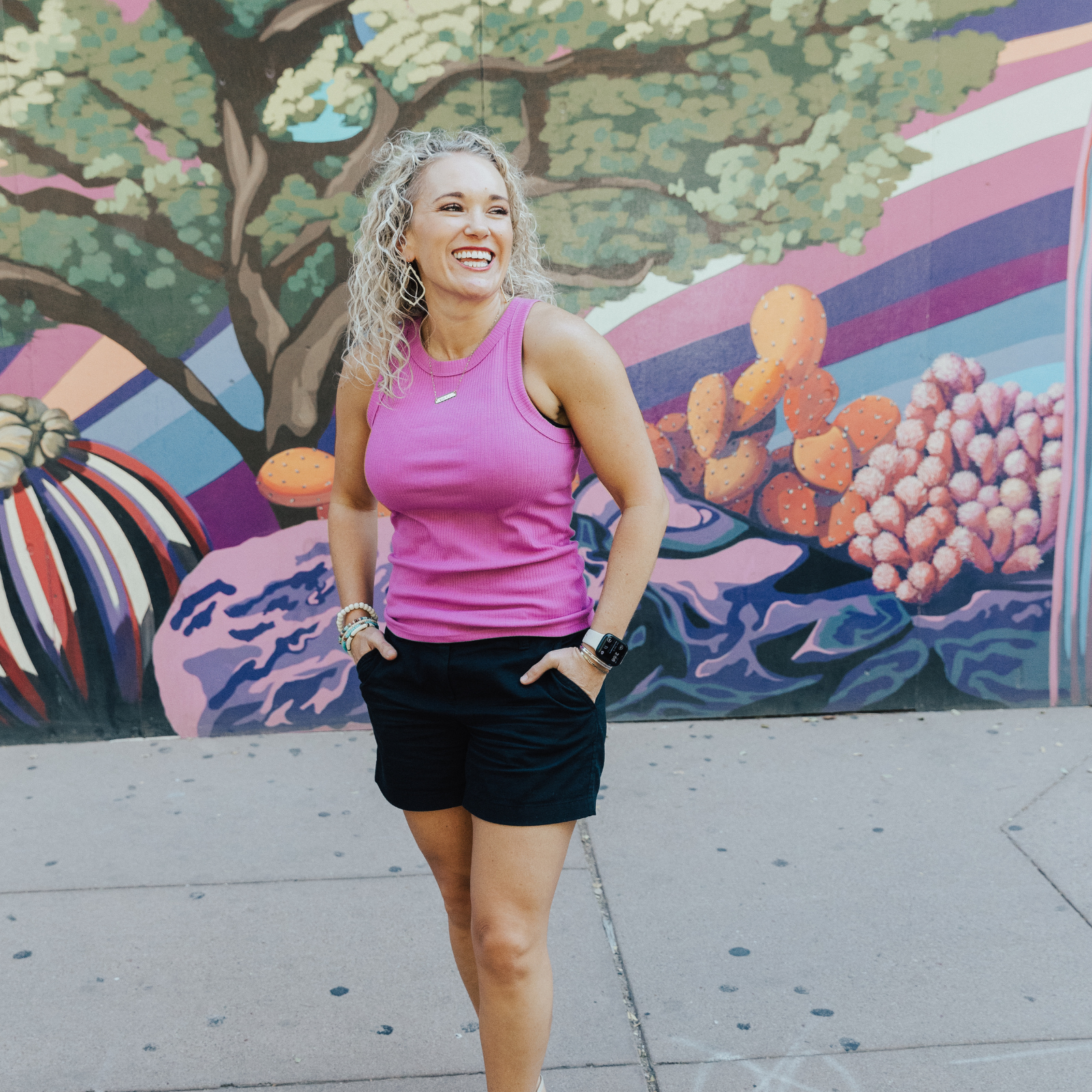 Image of Rachael DeBoy, founder of Wellness with Rachael, standing in front of a colorful mural and smiling. Rachael specializes in sourdough mentoring, financial guidance, insurance advocacy, and meal planning, helping individuals and families achieve holistic wellness.