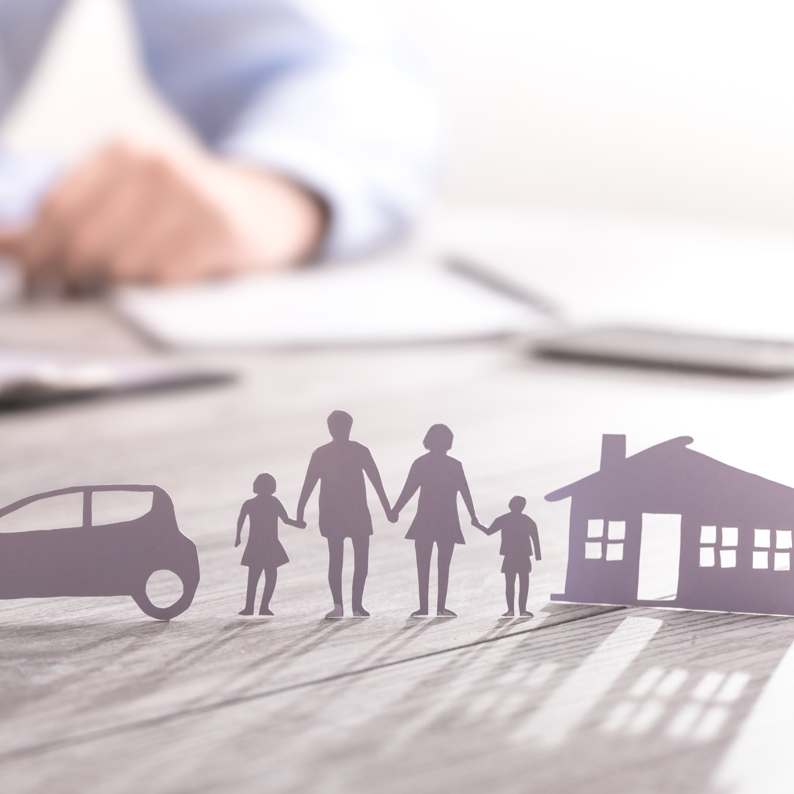 Essential Questions for Reviewing Your Insurance Policy "Silhouettes of a car, family, and house on a desk, symbolizing comprehensive insurance coverage with a professional reviewing documents in the background."