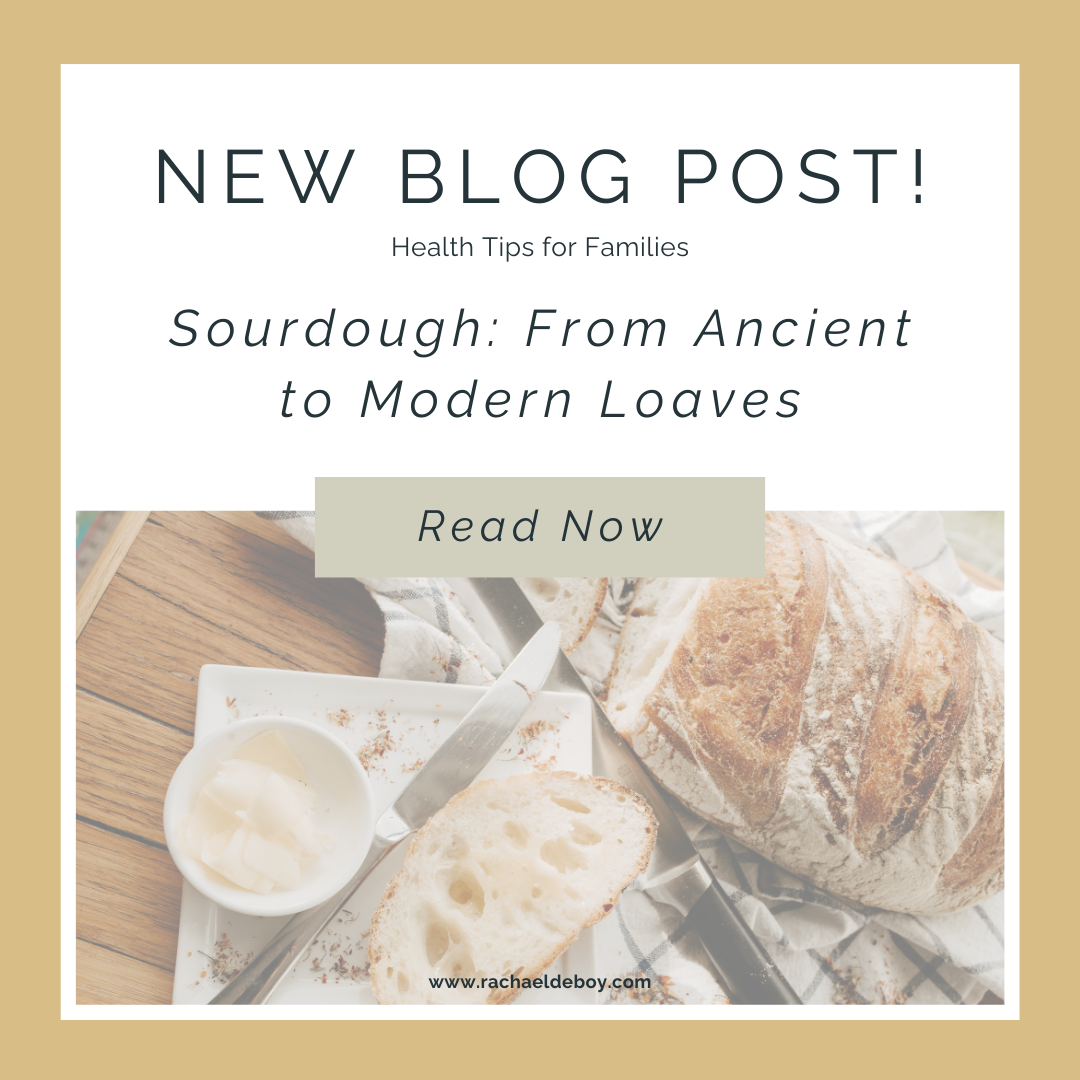 A rustic loaf of sourdough bread with a slice cut, served with butter on a wooden table.