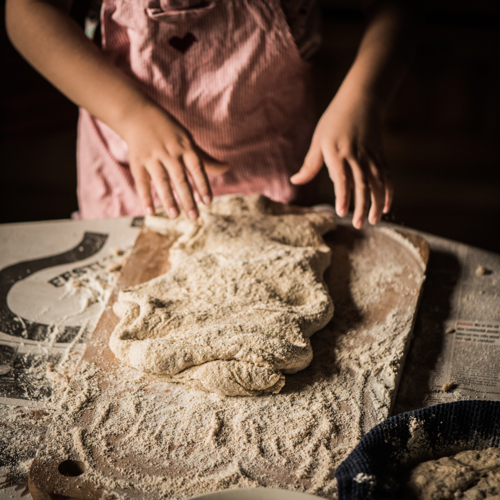 The Art of Sourdough: Hands-On Baking for Every Generation A child's hands shaping rustic sourdough dough on a wooden cutting board, dusted with flour.