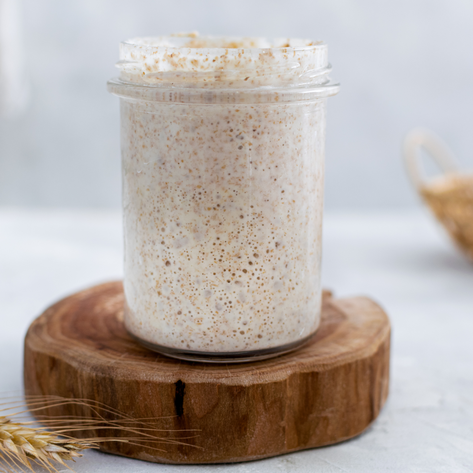Healthy Fermentation Starts Here: Sourdough Starter in Action Glass jar of active sourdough starter on wooden board, used for gut-friendly bread baking.