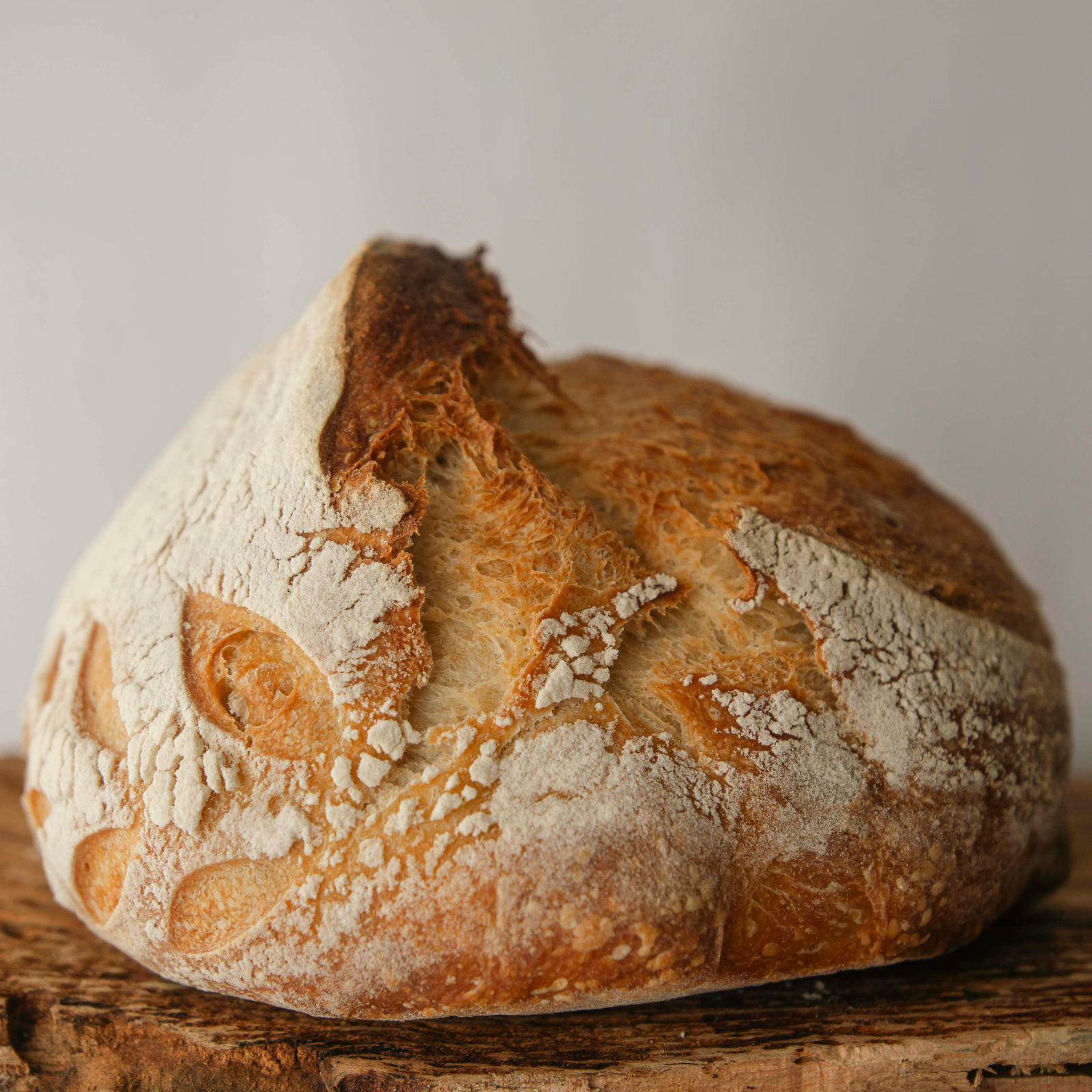 Golden Sourdough Loaf with Artisan Crust Perfection Golden brown artisan sourdough loaf with a crackly crust and decorative scoring on a wooden surface.