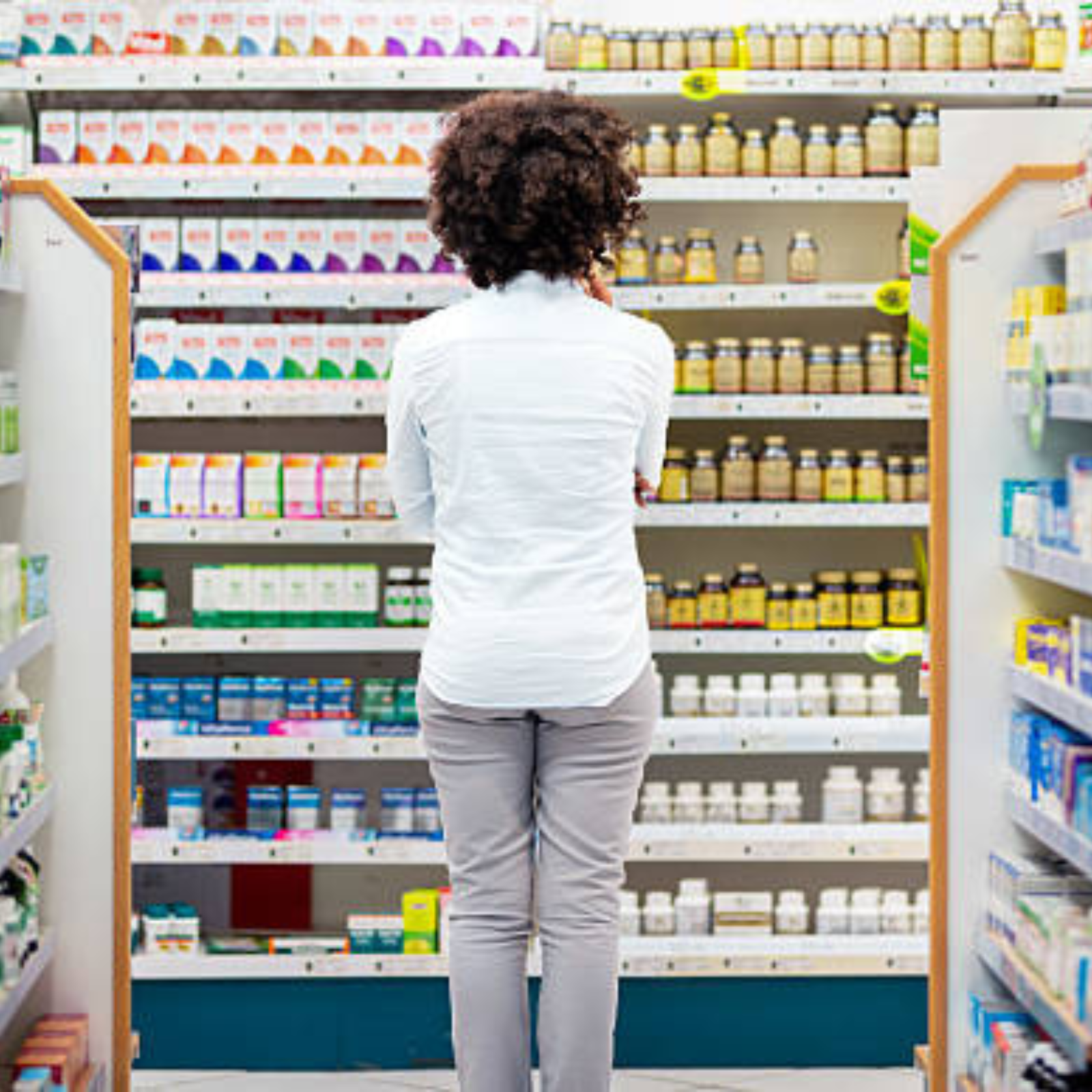 Choosing the Right Supplements: Juice Plus vs. Multivitamins Woman standing in front of supplement shelves evaluating vitamin options in a pharmacy.