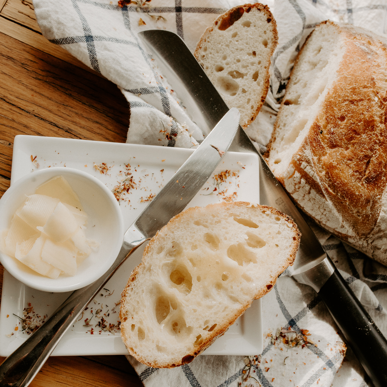 Rustic sourdough bread slices with butter on a white plate, supporting Rachael DeBoy’s wellness blog
