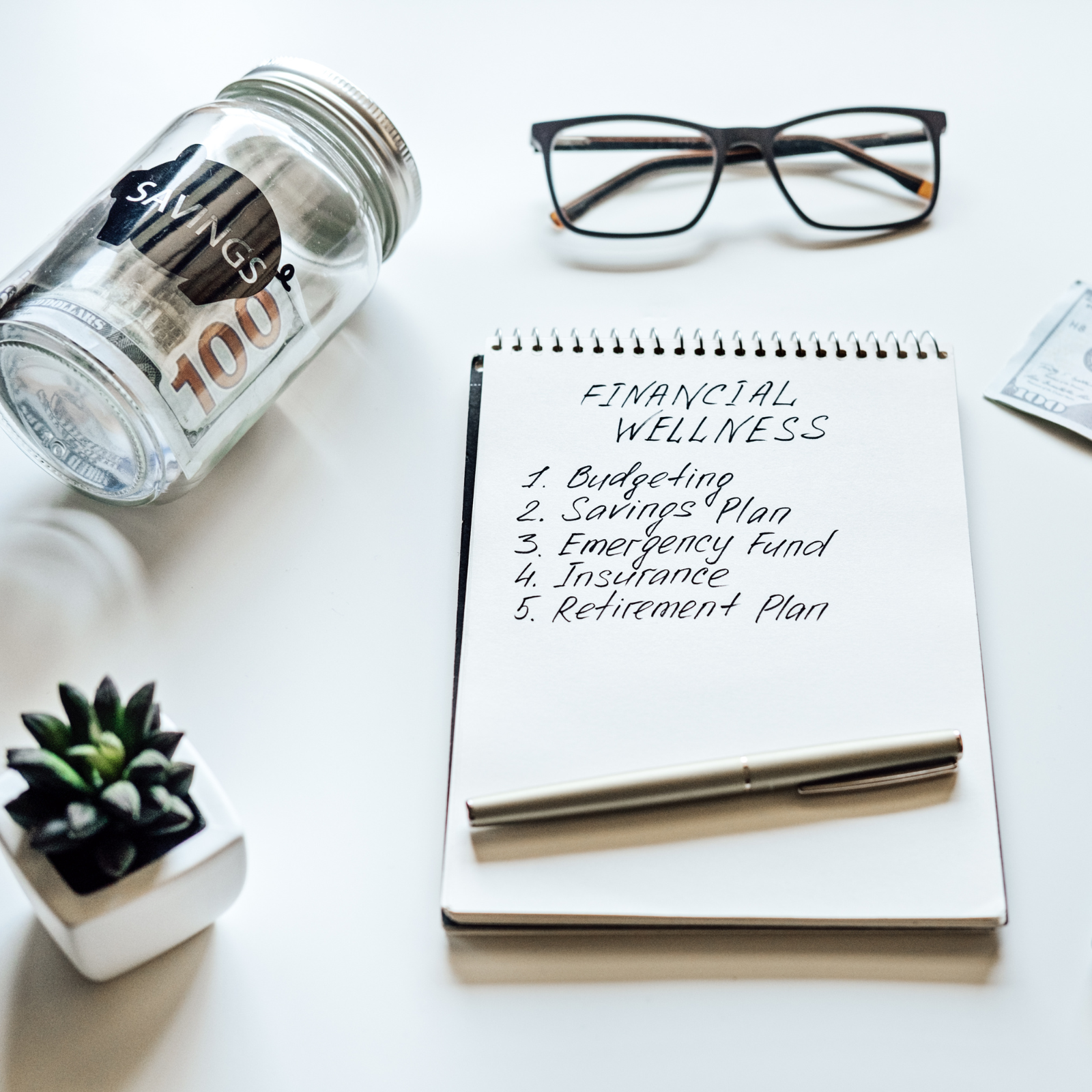Flat lay of a financial wellness checklist with a savings jar, glasses, and a pen representing smart money planning.