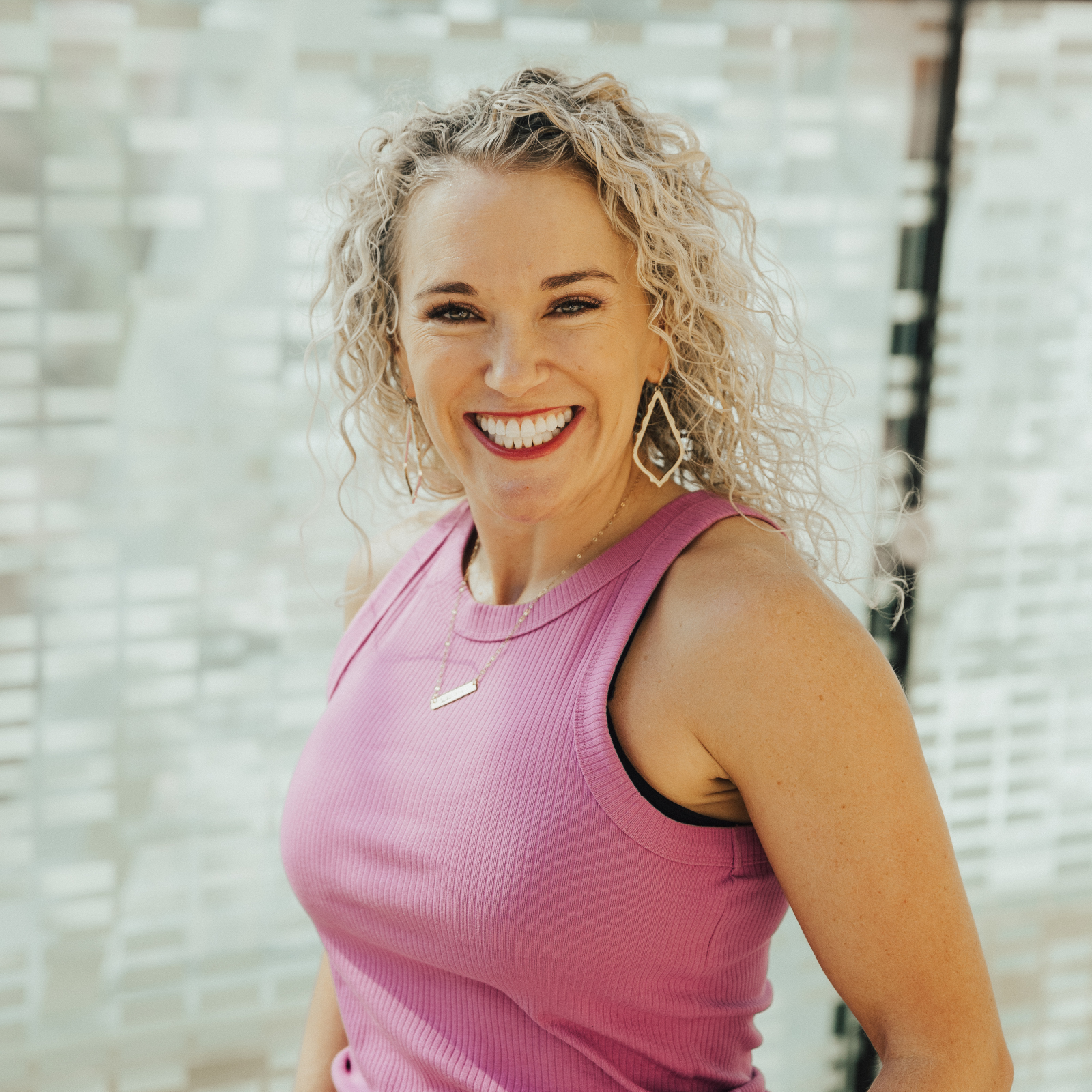 Rachael DeBoy smiling in a bright pink top, founder of Rachael DeBoy Wellness in San Antonio, Texas.